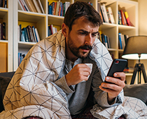 man drinking coffee or tea reading on a phone